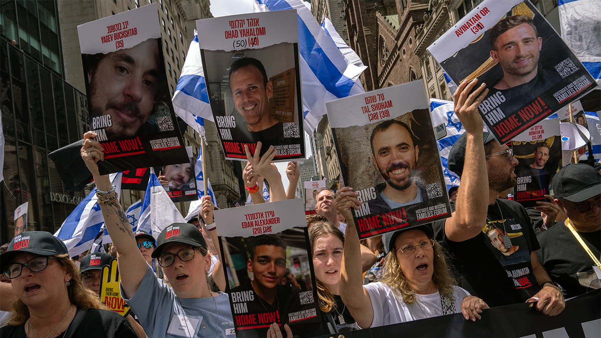 People, including the families of hostages, walk to the front holding 