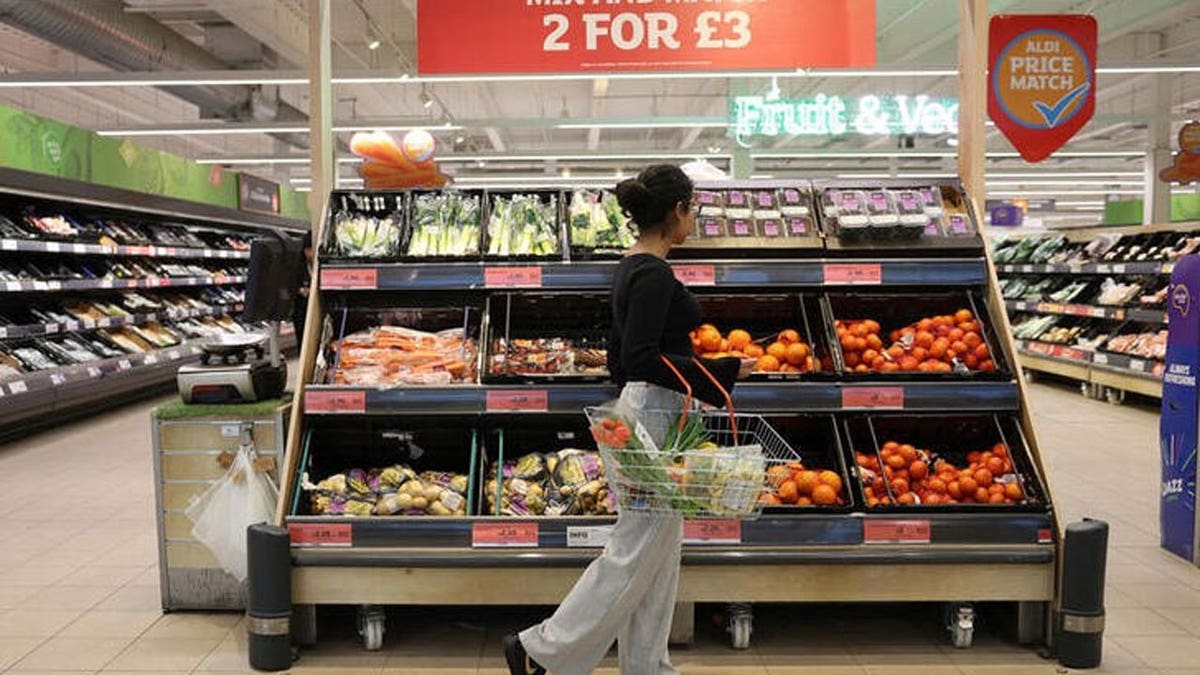 A customer walks in front of a fruit display in a supermarket