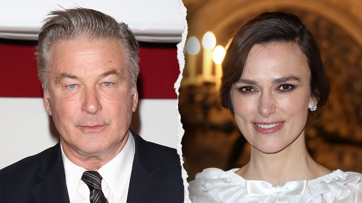 Alec Baldwin in a dark suit looks serious staring at the camera on the carpet split Keira Knightley in a white dress smiles for a picture