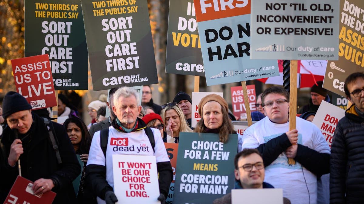 opponents to a bill to legalize assisted dying holding signs