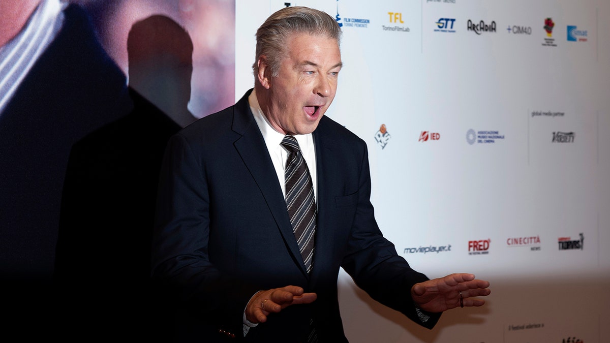 Alec Baldwin on the carpet at the Turino Film Festival with his mouth ajar looks excited 