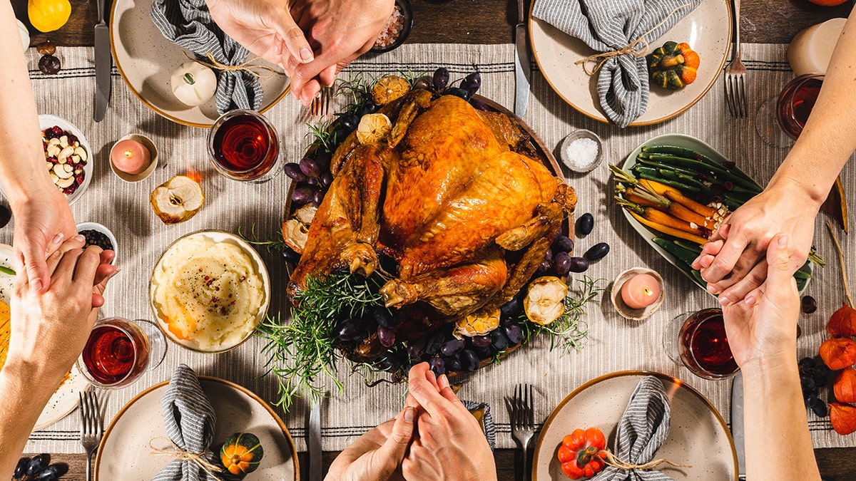 Family praying around Thanksgiving feast