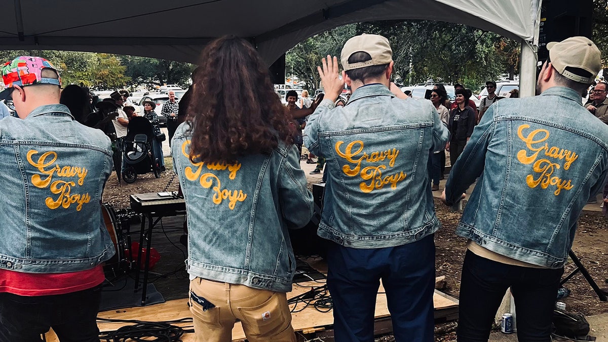 Four men wearing jean jackets reading 