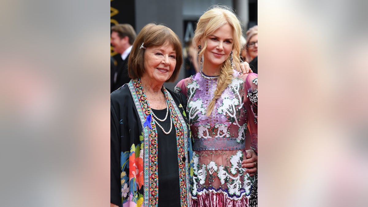 A close-up of Nicole Kidman and her mother posing together and smiling as they both wear multiprinted dresses.