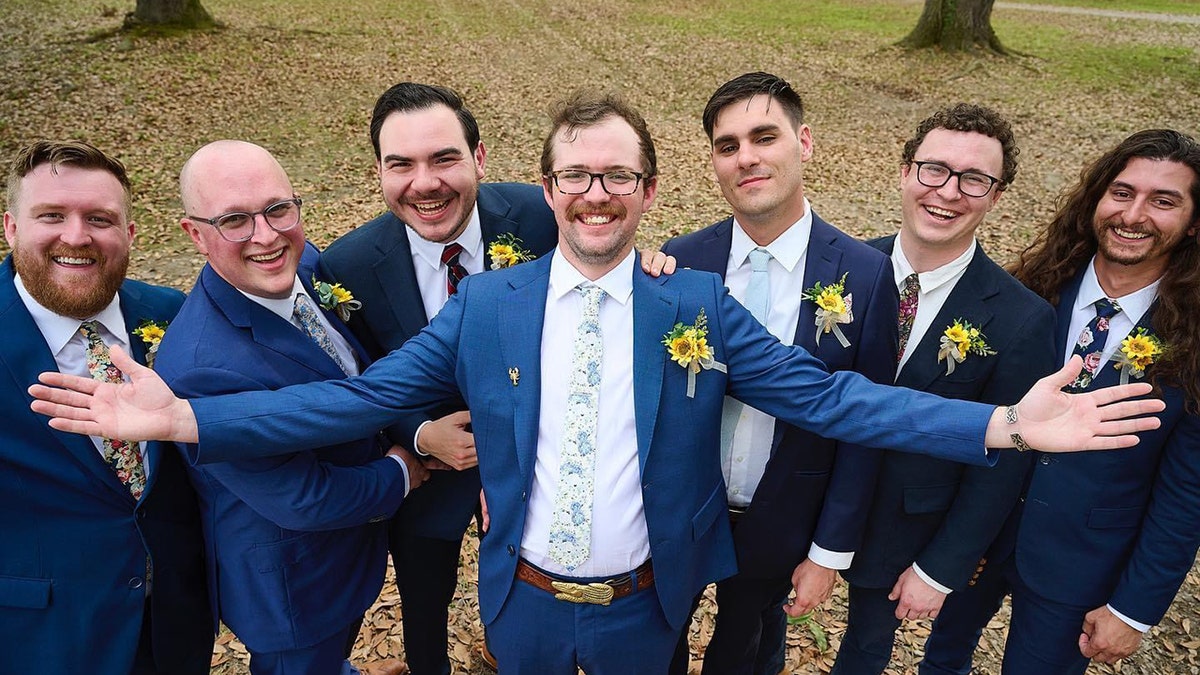 Seven men at a wedding, with a groom in the center.