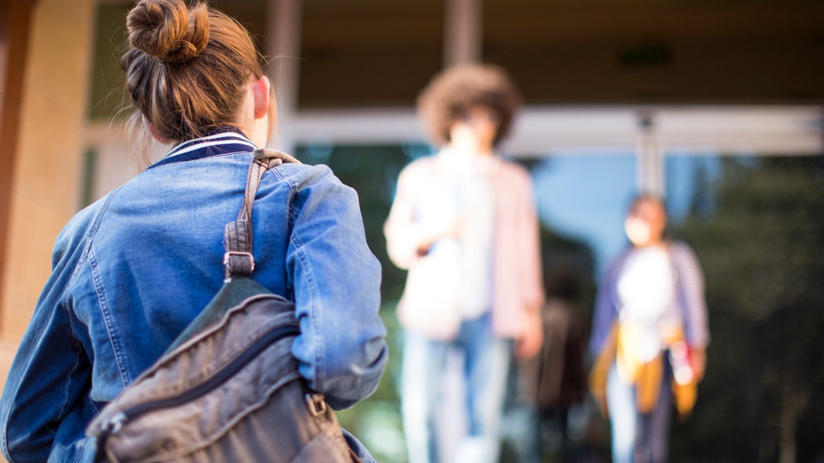 Young students on campus walking into building.