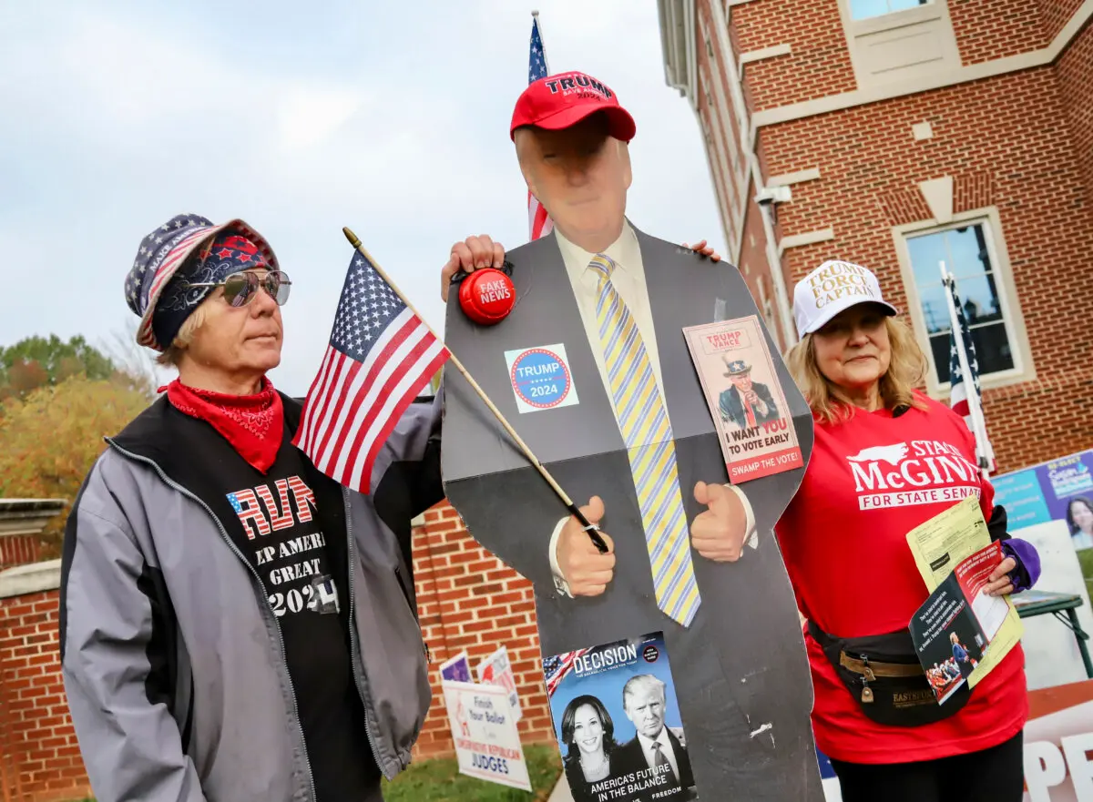 Debby and Johnny Presson of Mint Hill set up their table, complete with a cardboard cutout of Donald Trump, outside the Mint Hill Town Hall precinct in Mint Hill, N.C., on Nov. 5, 2024. The Pressons volunteer with the Mecklenburg County GOP. (Jennifer Podis for The Epoch Times)