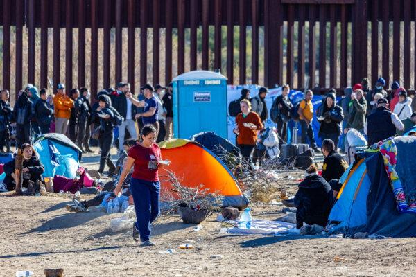 Illegal immigrants who passed through a gap in the U.S. border wall await processing by border patrol agents in Jacumba, Calif., on Dec. 6, 2023. (John Fredricks/The Epoch Times)