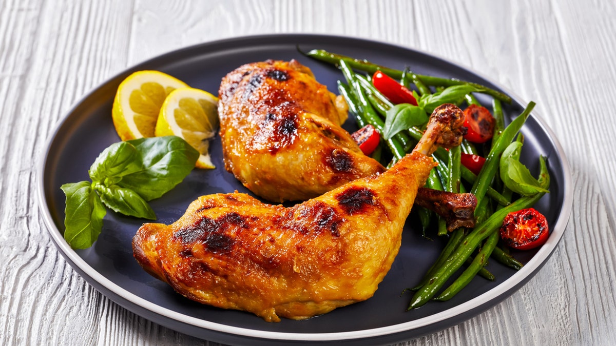 roast chicken legs with green beans, lemon, fried tomatoes and fresh basil on plate