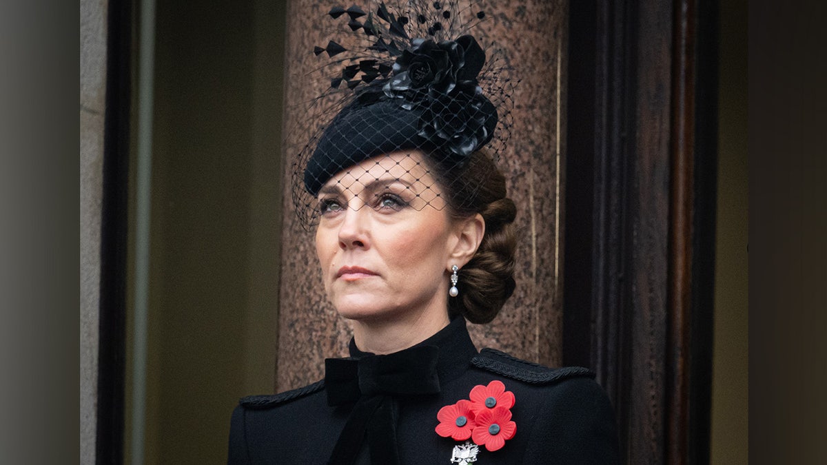 Close up of Kate Middleton in black dress and fascinator, wearing a poppy pin