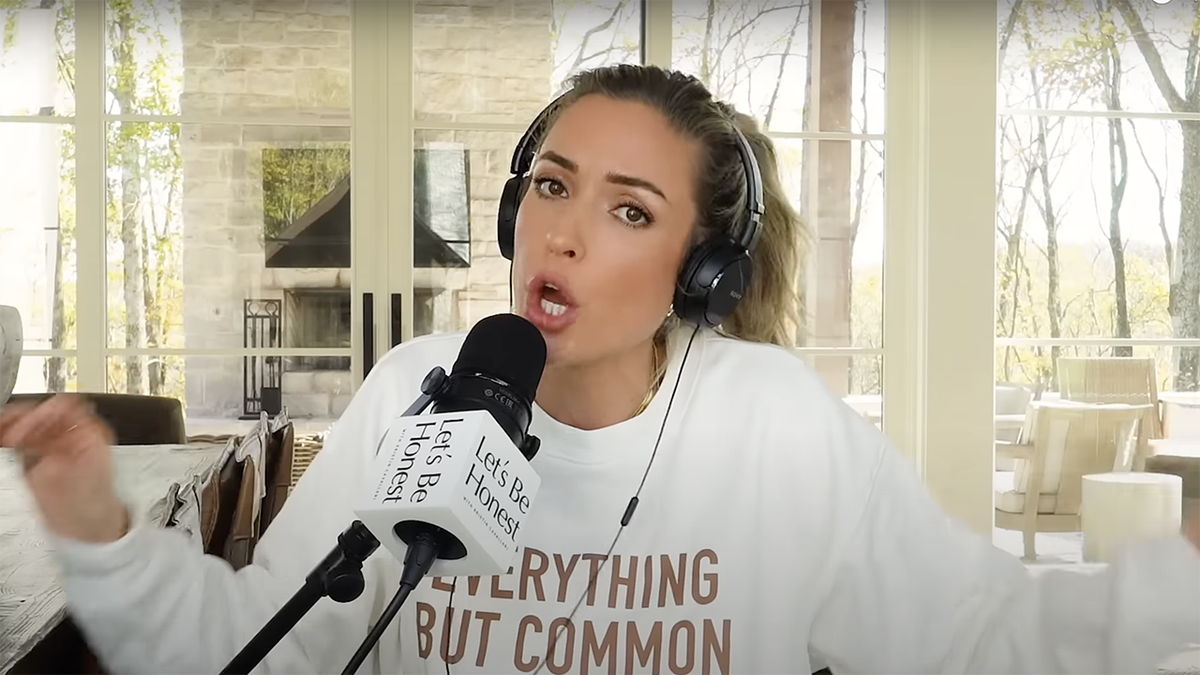 Kristin Cavallari wears a sweatshirt and big black earphones while she animatedly speaks into her podcast microphone 