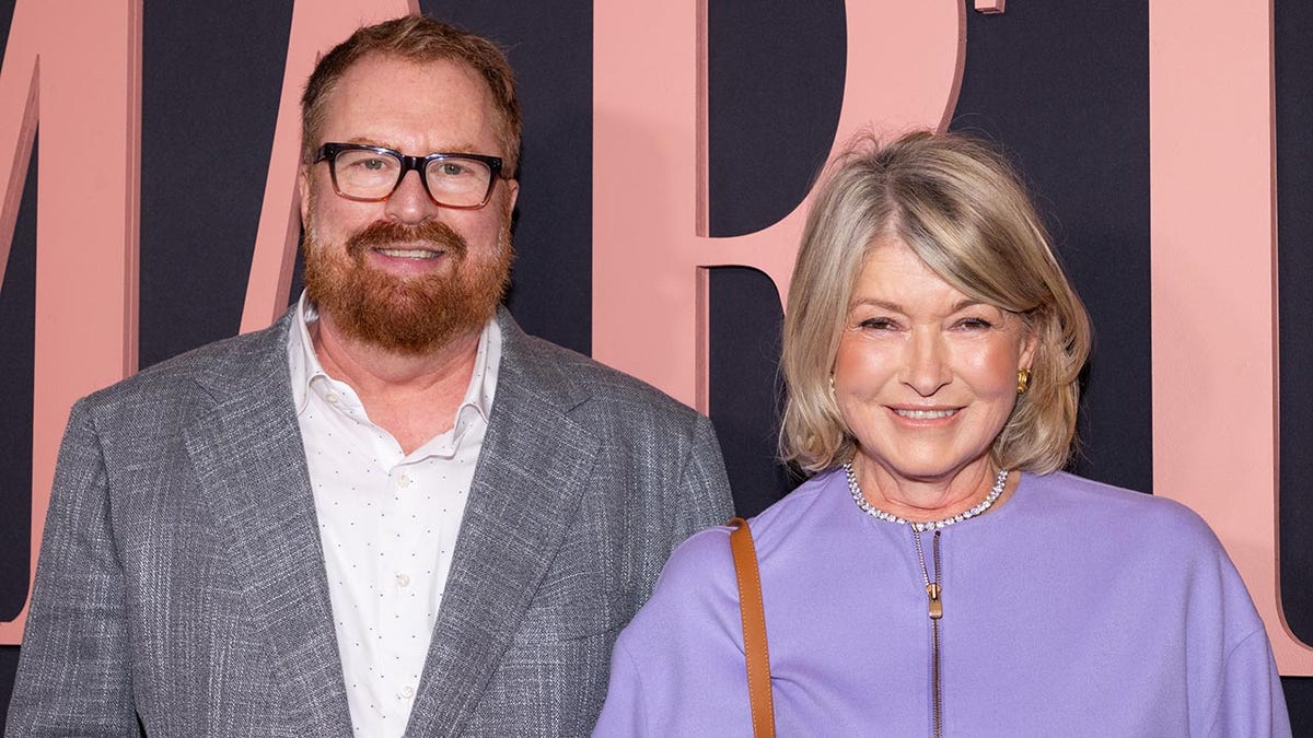 R.J. Cutler in a grey suit smiles at the premiere of 