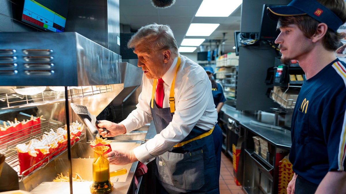 Republican presidential nominee and former President Donald Trump, left, uses a frier as an employee looks on during a visit to McDonald's in Feasterville-Trevose, Pa., Sunday, Oct. 20, 2024.