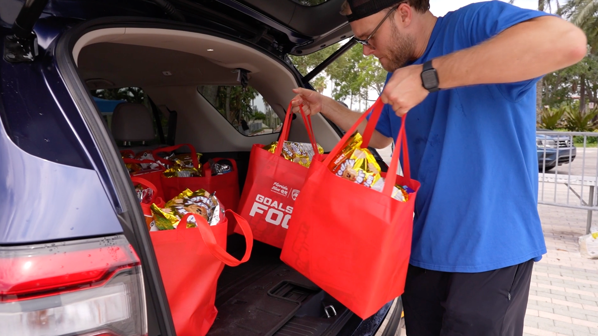 A volunteer loads a bag of food into the back of a vehicle outside Amerant Bank Arena in Sunrise, Florida.