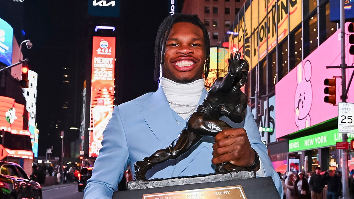 Travis Hunter smiles with Heisman Trophy