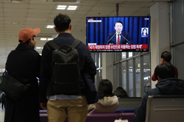 People watch a TV screen showing South Korean President Yoon Suk Yeol's televised briefing at a bus terminal in Seoul, South Korea, Tuesday, Dec. 3, 2024. (AP Photo/Ahn Young-joon)