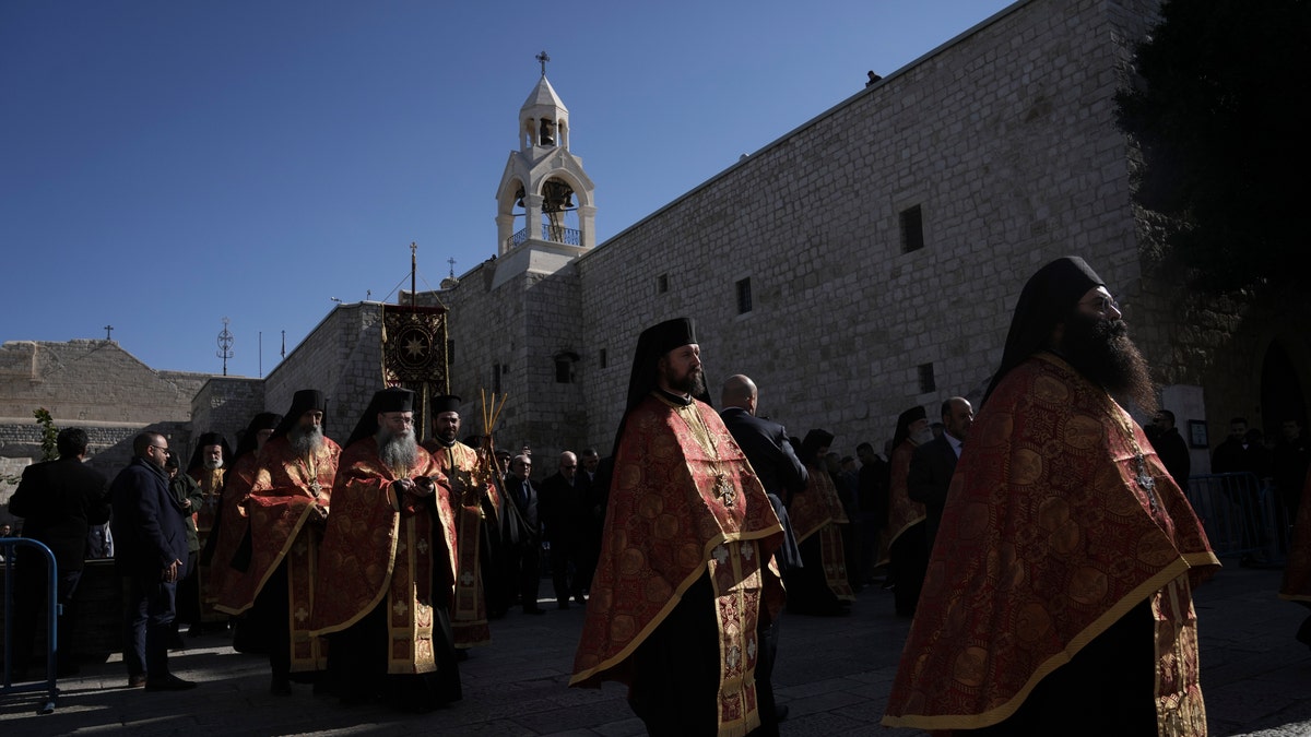 Orthodox priests walk outside of the Nativity Church