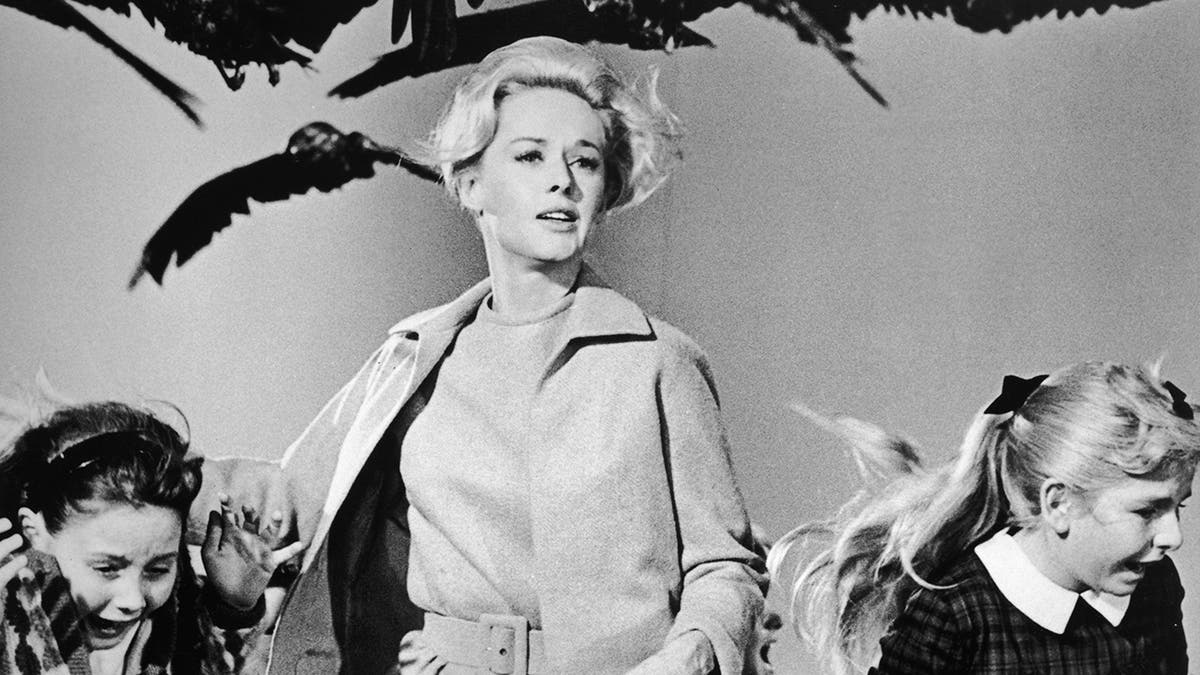 Tippi Hedren running away from birds as she holds onto two little girls