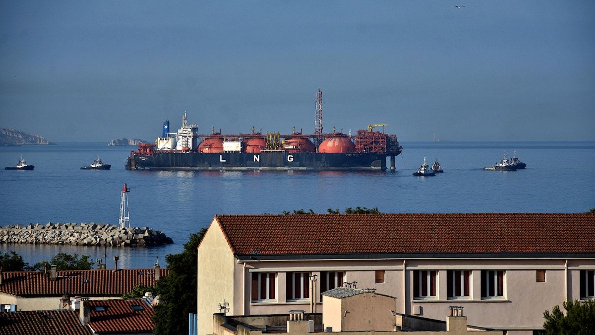 LNG tanker in background, houses along shoreline