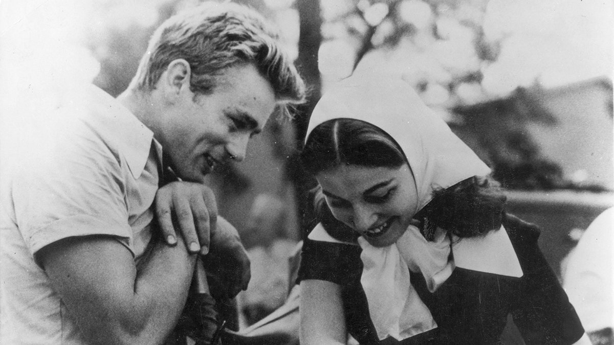 James Dean smiling at Pier Angeli who has her hair wrapped with a scarf.