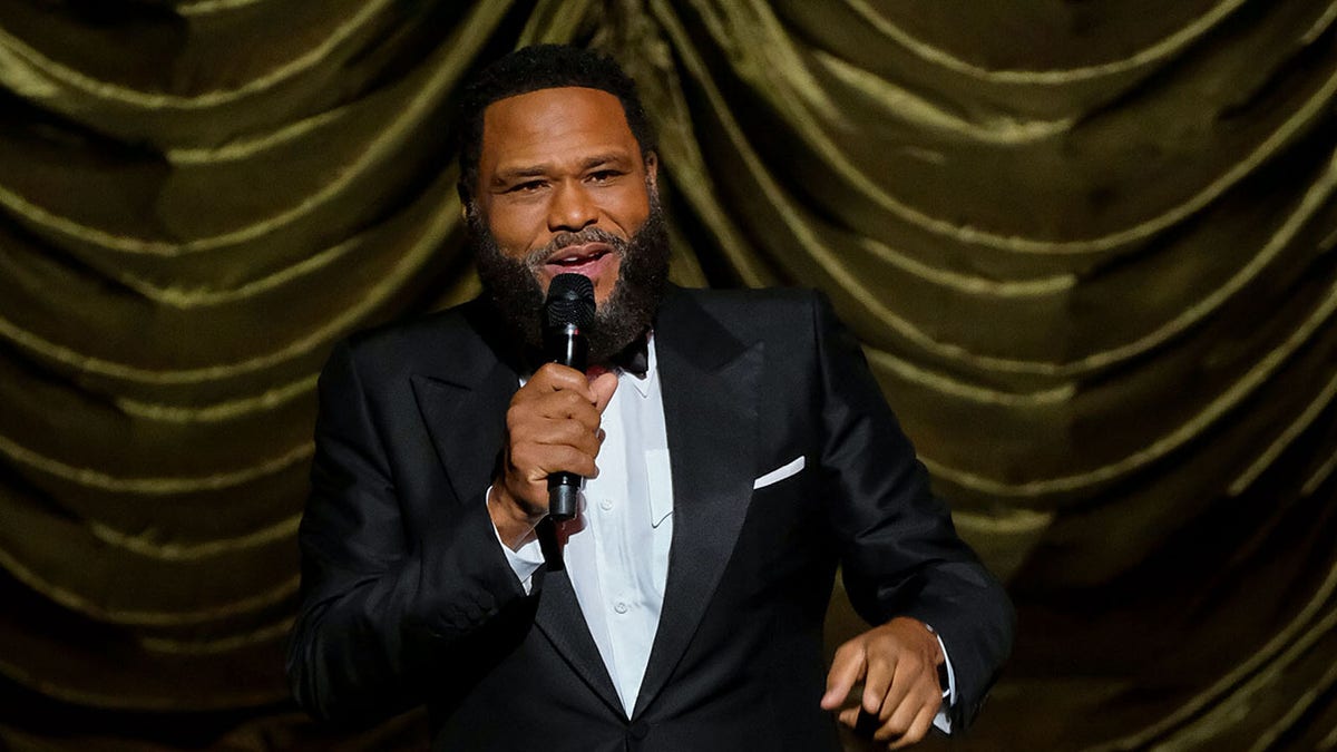 Anthony Anderson speaking on stage wearing a tuxedo