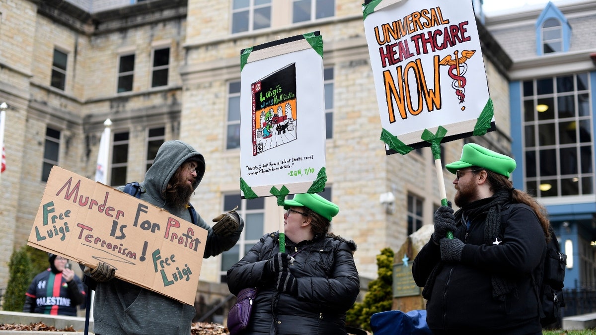 Adam Giesseman, left, of Piqua, Ohio, Ashlyn Adami, center, of South Bend, Ind., and Ethan Merrill of South Bend, Ind., protest outside the Blair County Courthouse after a hearing for Luigi Nicholas Mangione