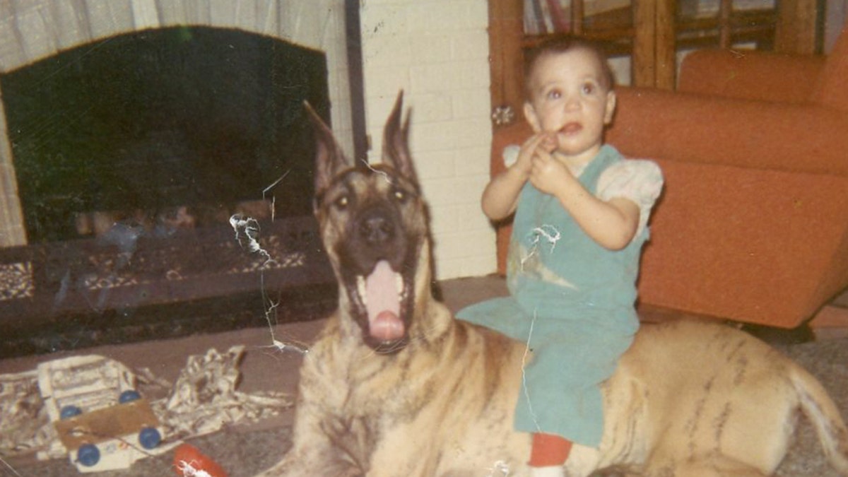 April Balascio sitting on top of a dog.