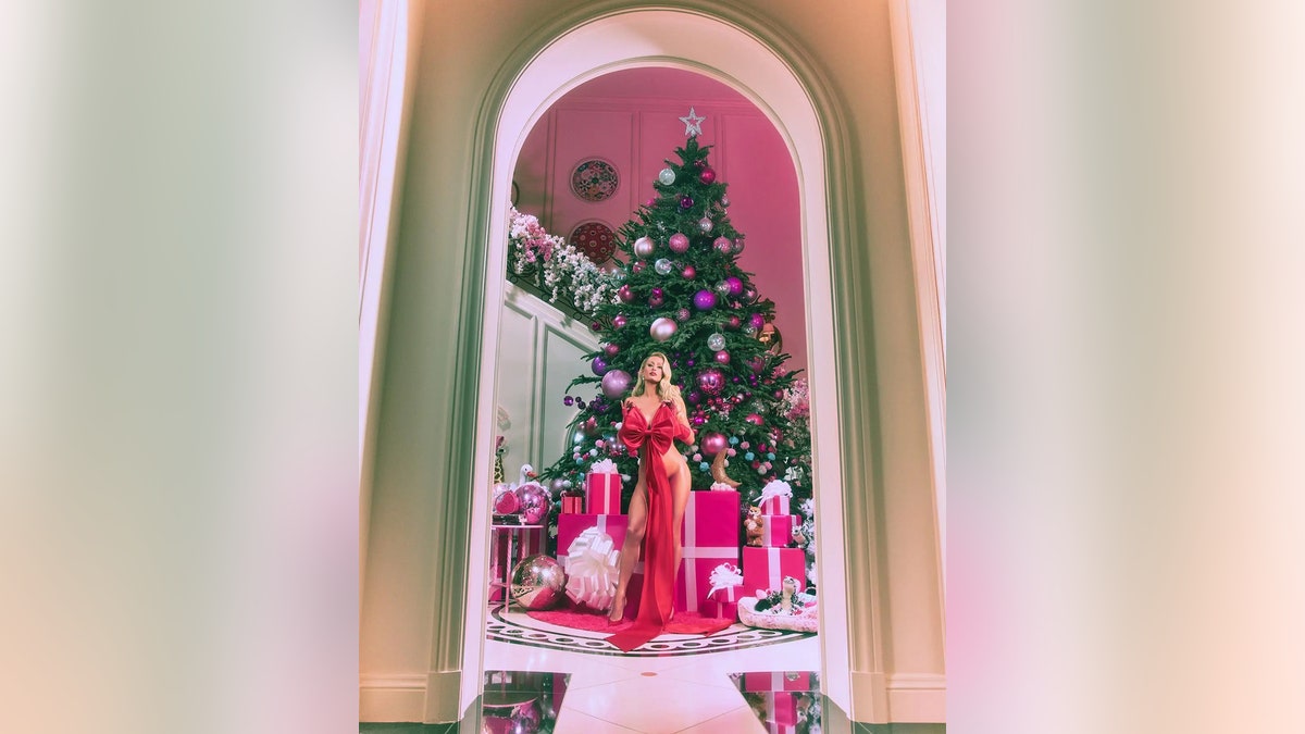 Paris Hilton standing in front of a tree surrounded by presents.