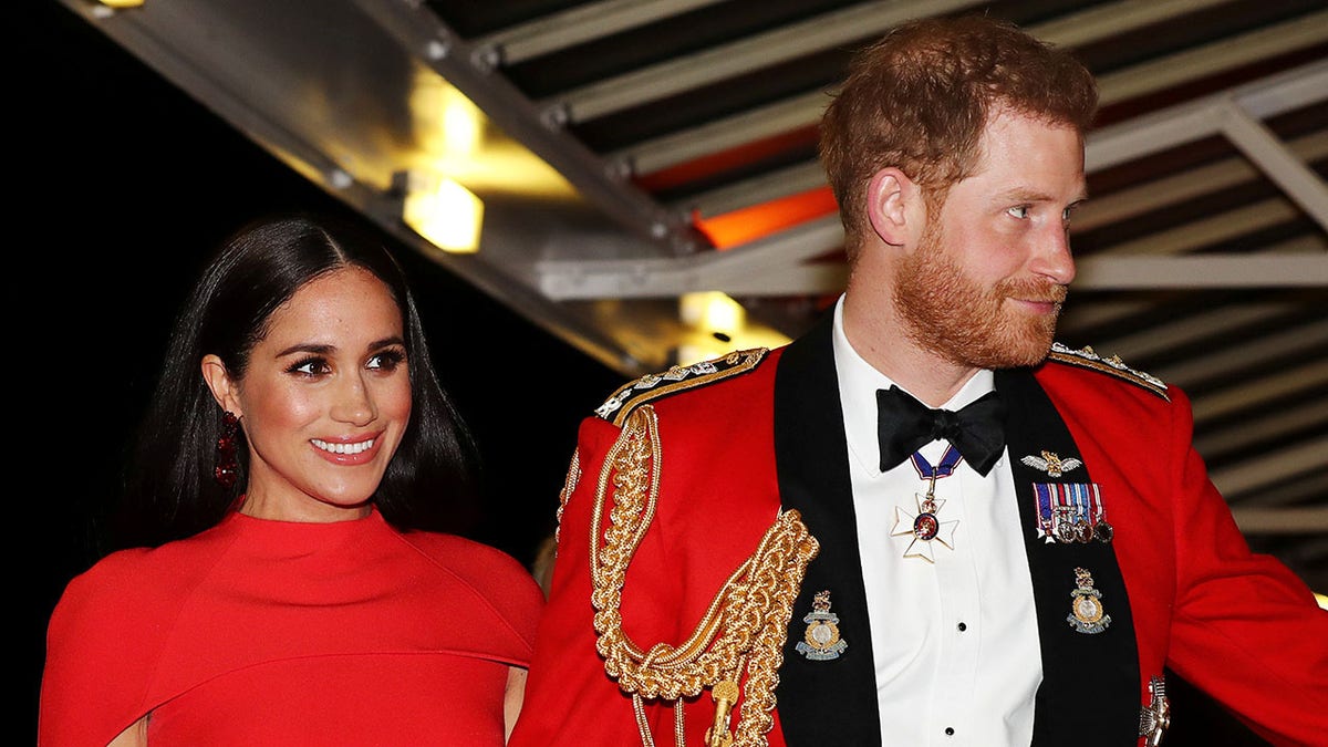 Meghan Markle and Prince Harry wearing matching formal red attire.