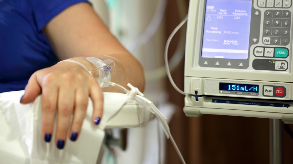 Infusion pump feeding IV drip into patients arm focus on needle