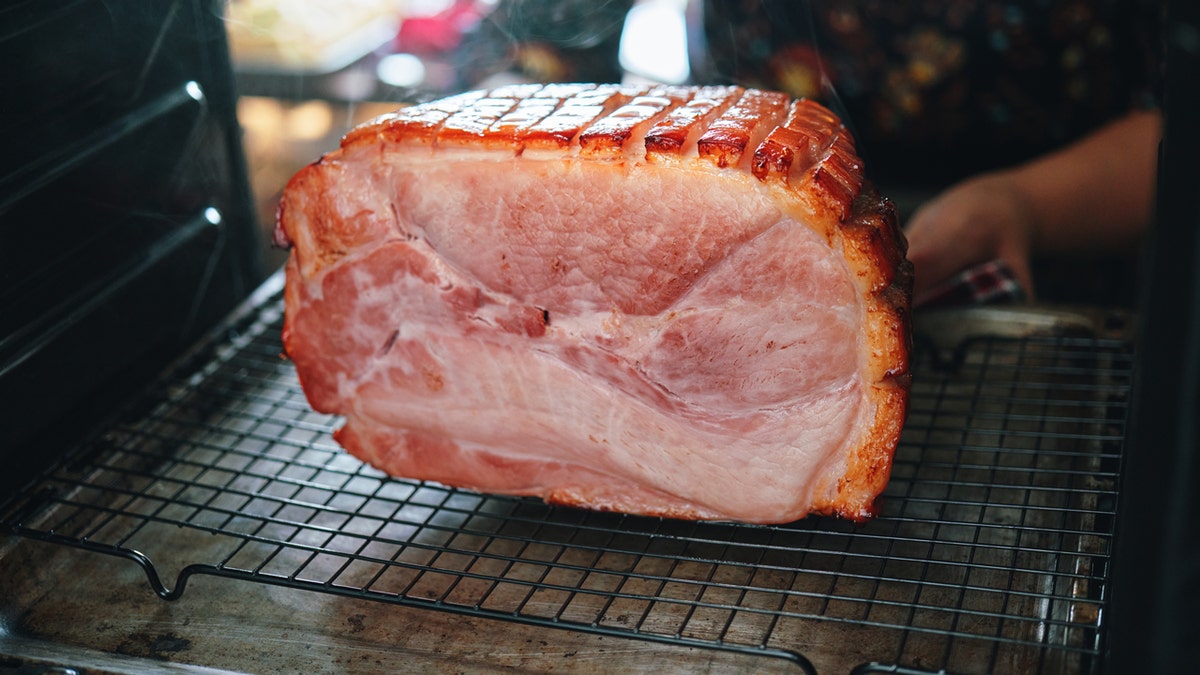 A person checks on a Christmas ham in an oven.