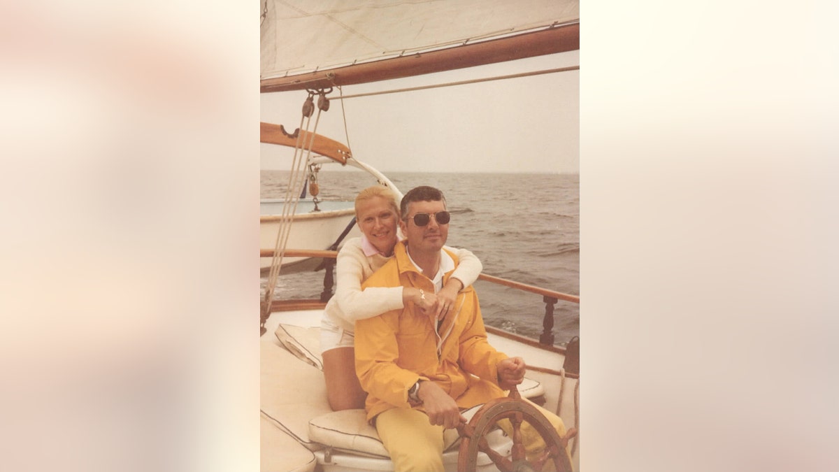 Doreen Boyle wearing white wrapping her arms around John Boyle wearing a yellow jacket.