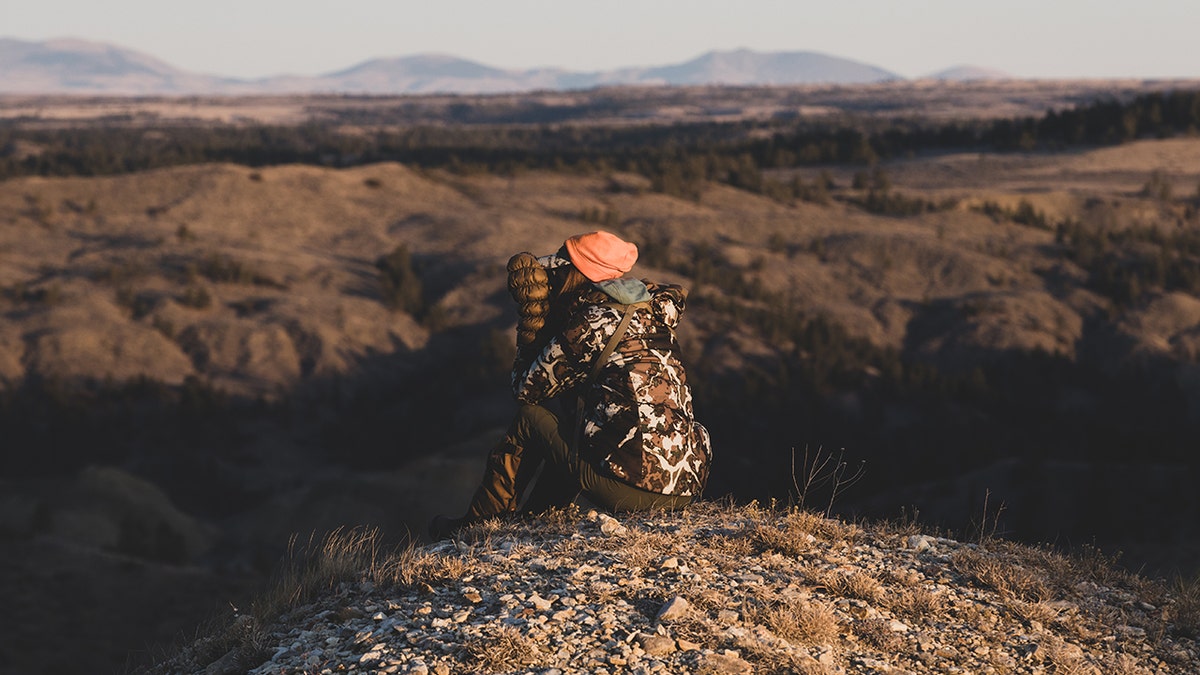 Danielle Prewett uses binoculars to look out from her vantage point while hunting.