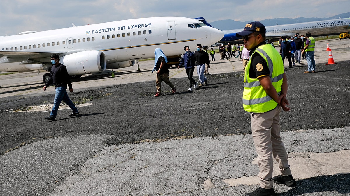 A police officer stands by as migrants are returned to Guatemala.