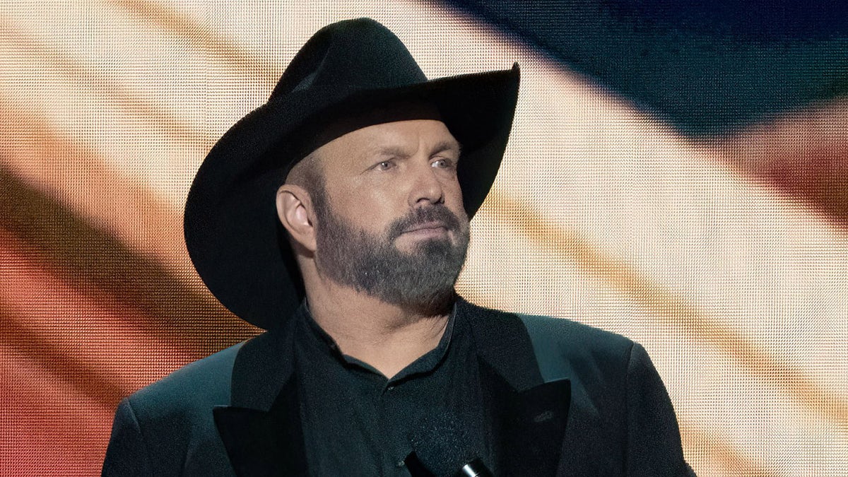 Garth Brooks performs earing signature black hat and coat