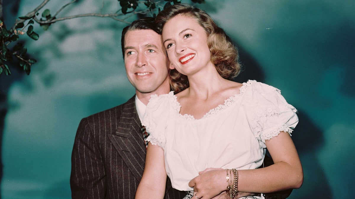 James Sewart smiling while holding onto Donna Reed wearing a white frilly blouse.