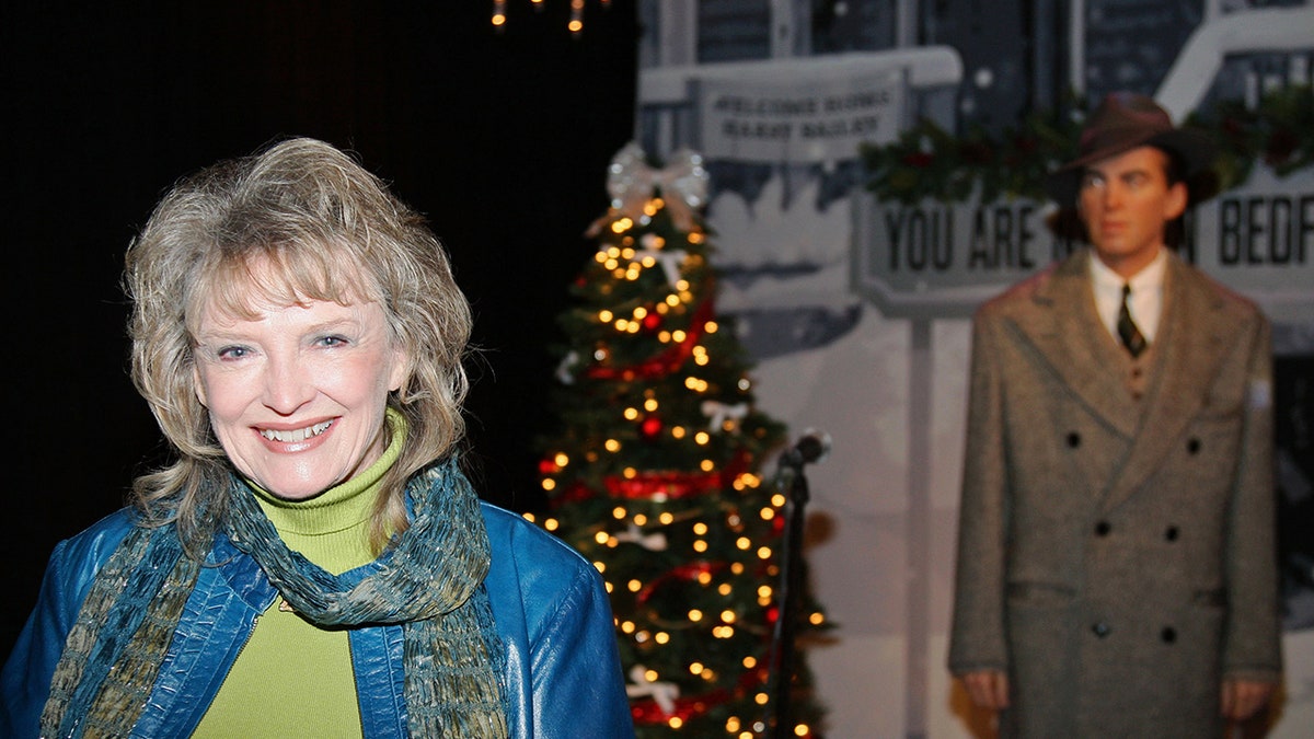 Karolyn Grimes smiling in a blue jacket with a green turtleneck sweater