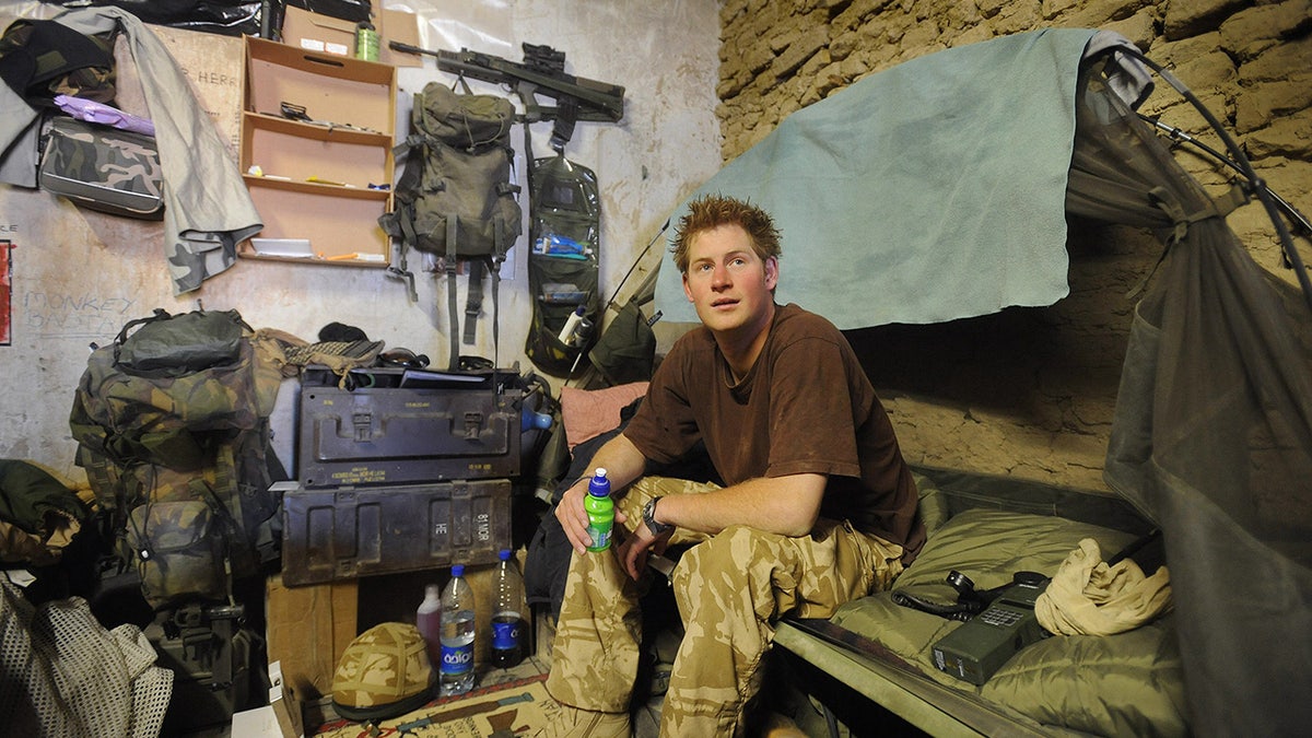 Prince Harry in military gear sitting inside a tent.