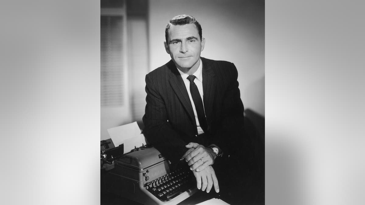 Rod Serling next to a typewriter while wearing a suit.