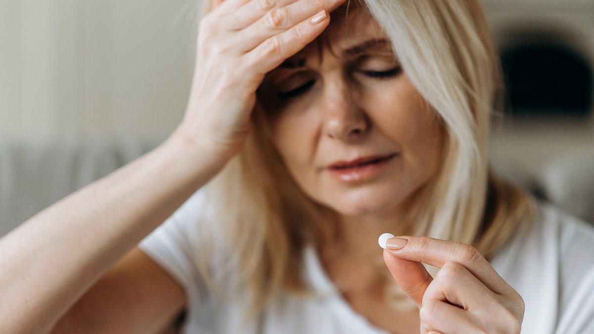 woman with headache takes pill