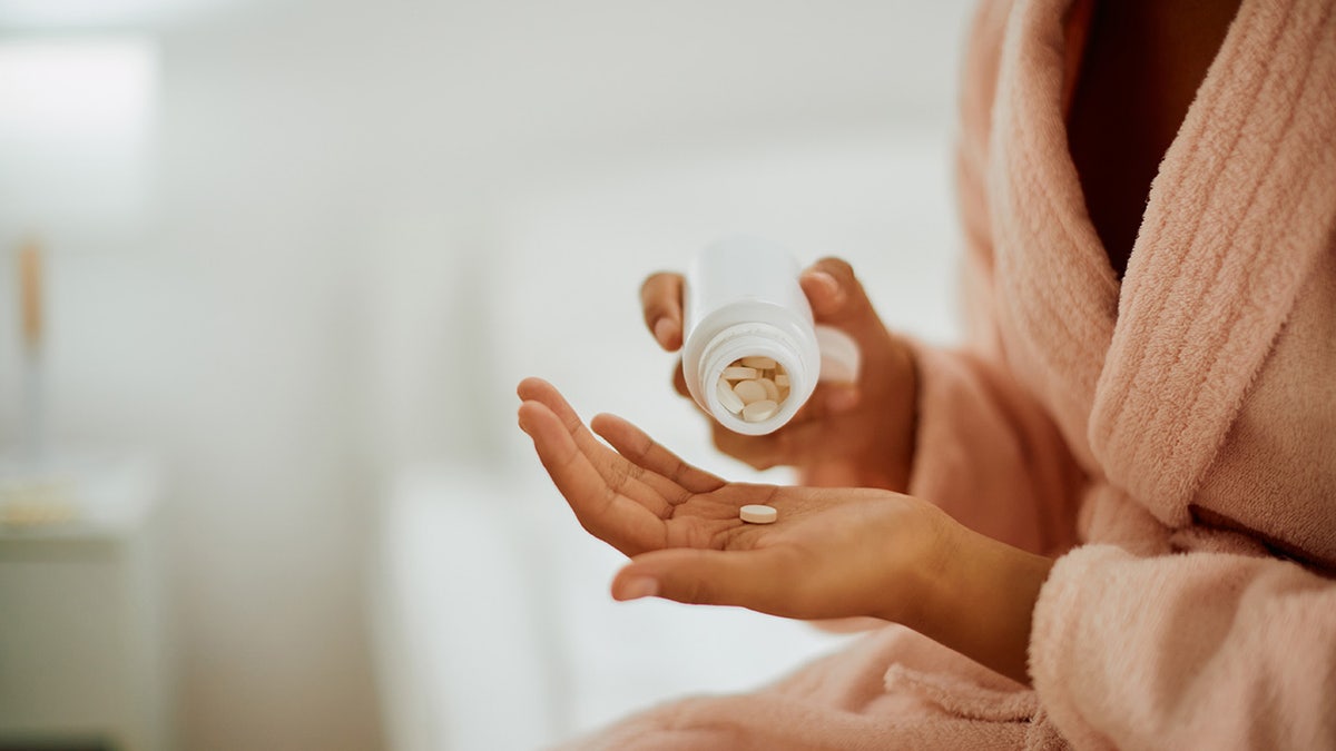 Close-up of woman taking medicine at home.