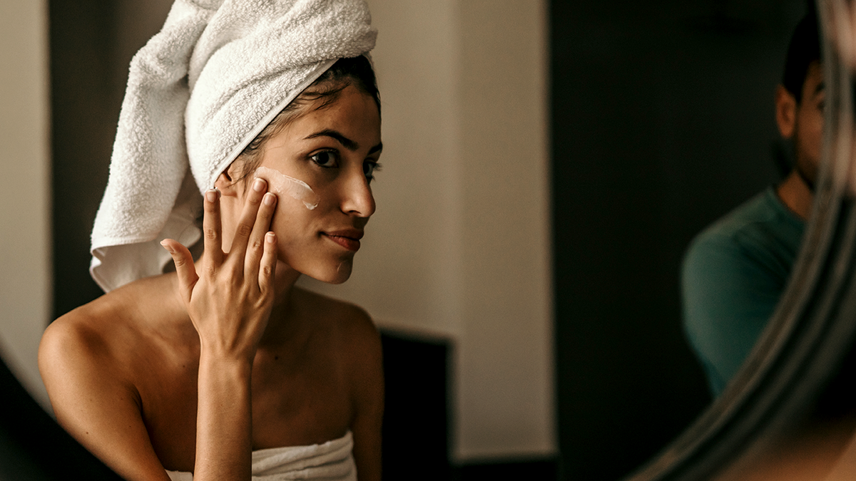 woman puts moisturizer on face