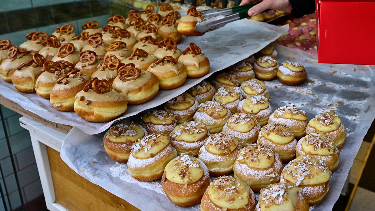 A man buys sufganiyot, a round jelly doughnut eaten in Israel and around the world on the Jewish festival of Hanukkah