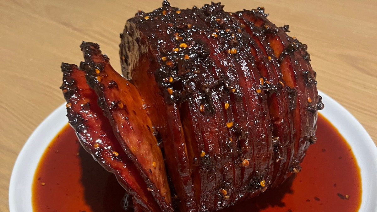 A holiday ham made by chef Buddha Lo is shown with glaze on the bottom of the plate.