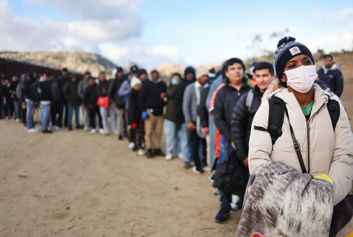 Illegal immigrants stand along the U.S.-Mexico border as they await processing by the U.S. Border Patrol in Jacumba Hot Springs, Calif., on Dec. 1, 2023. (Mario Tama/Getty Images)