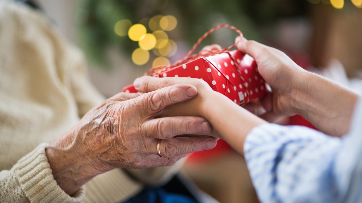 Close-up of hands of senior and young woman holding a present at Christmas time.