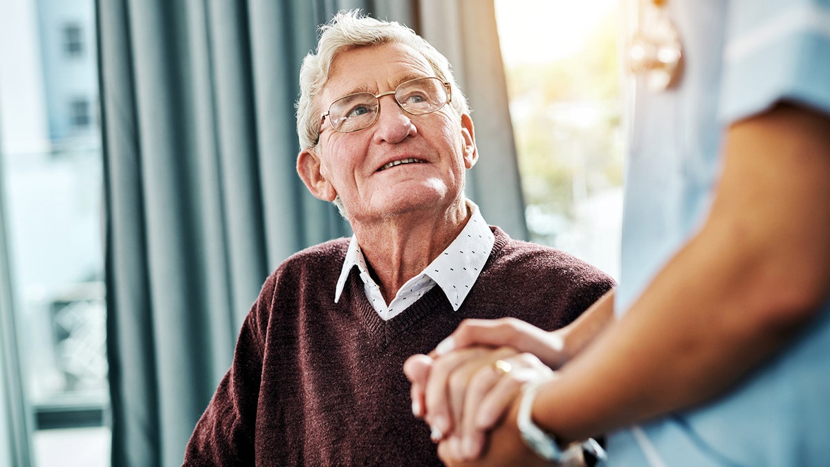 nurse holding hands with a senior patient