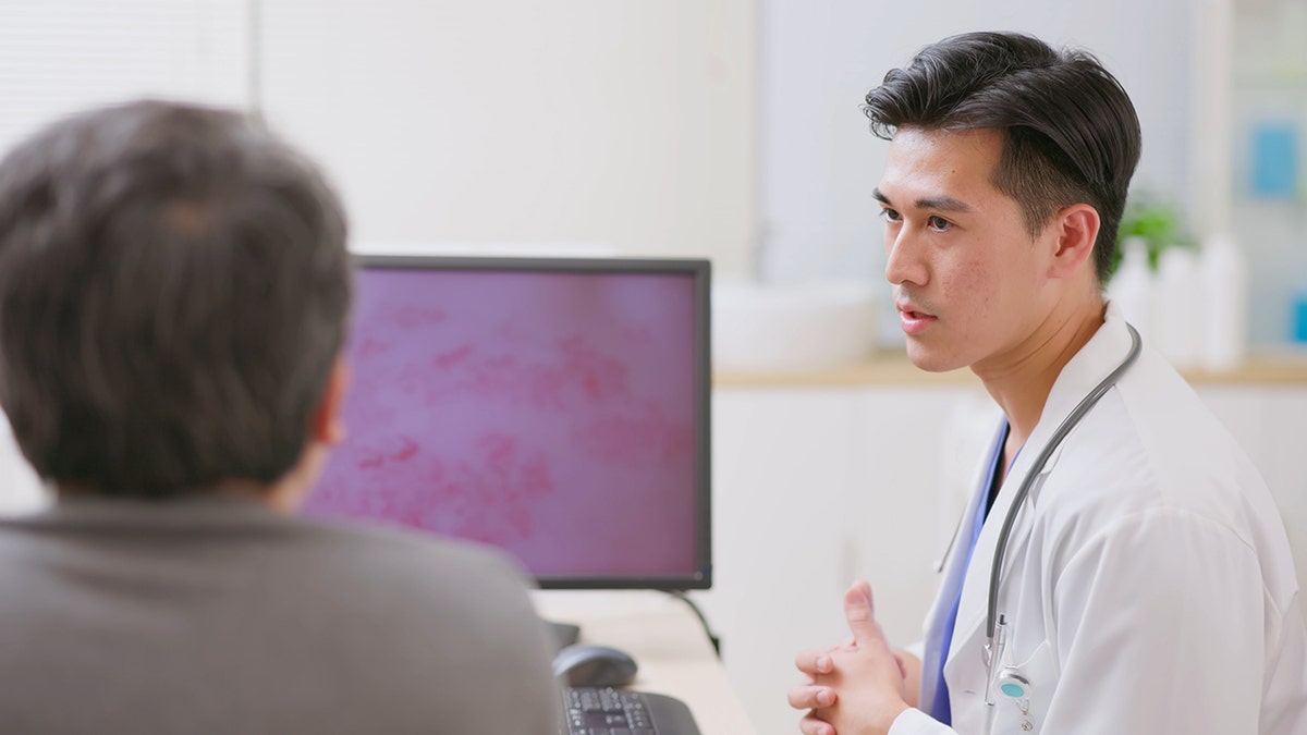 doctor explaining to male patient about skin condition