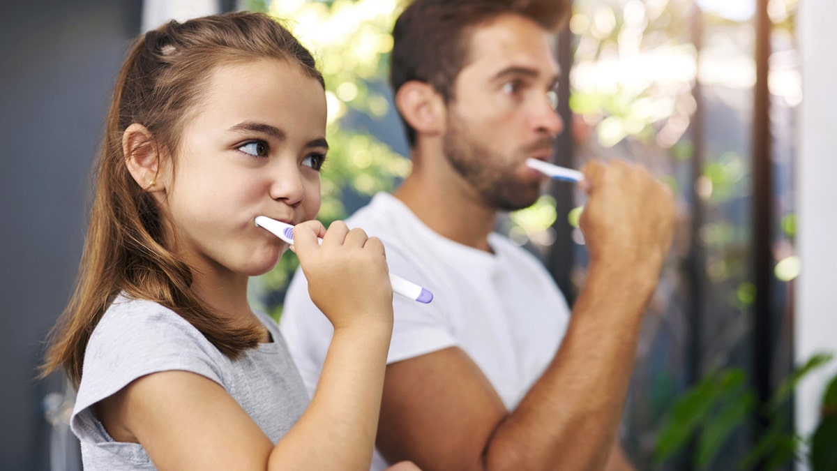 father daughter brushing teeth together