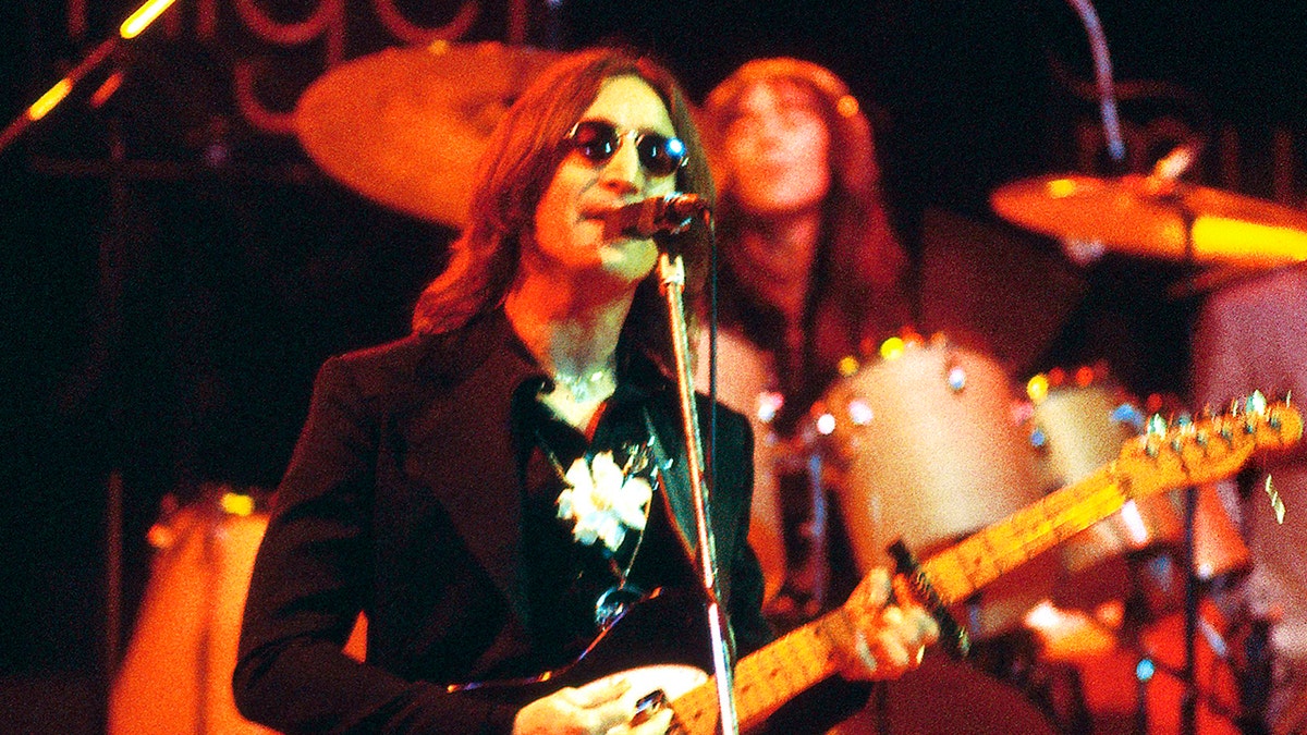 John Lennon wearing a gardenia in his lapel on stage